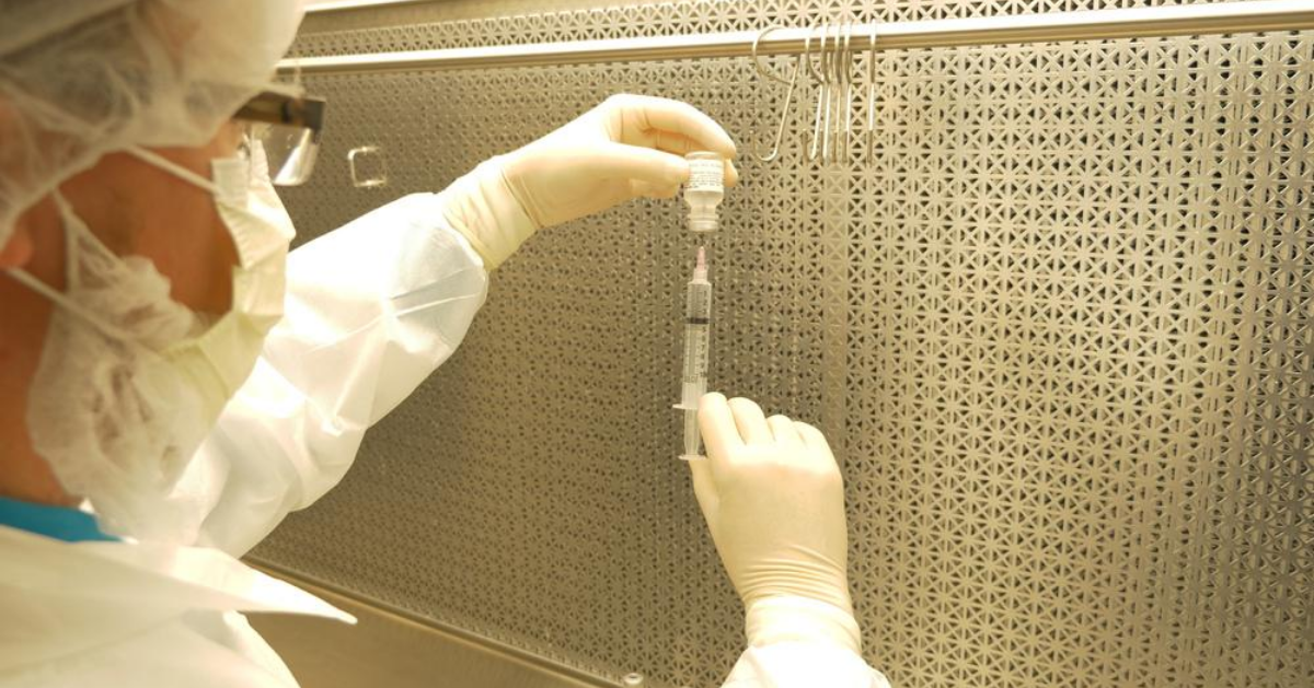 Pharmacist drawing up fluid from a vial in a laminar flow hood