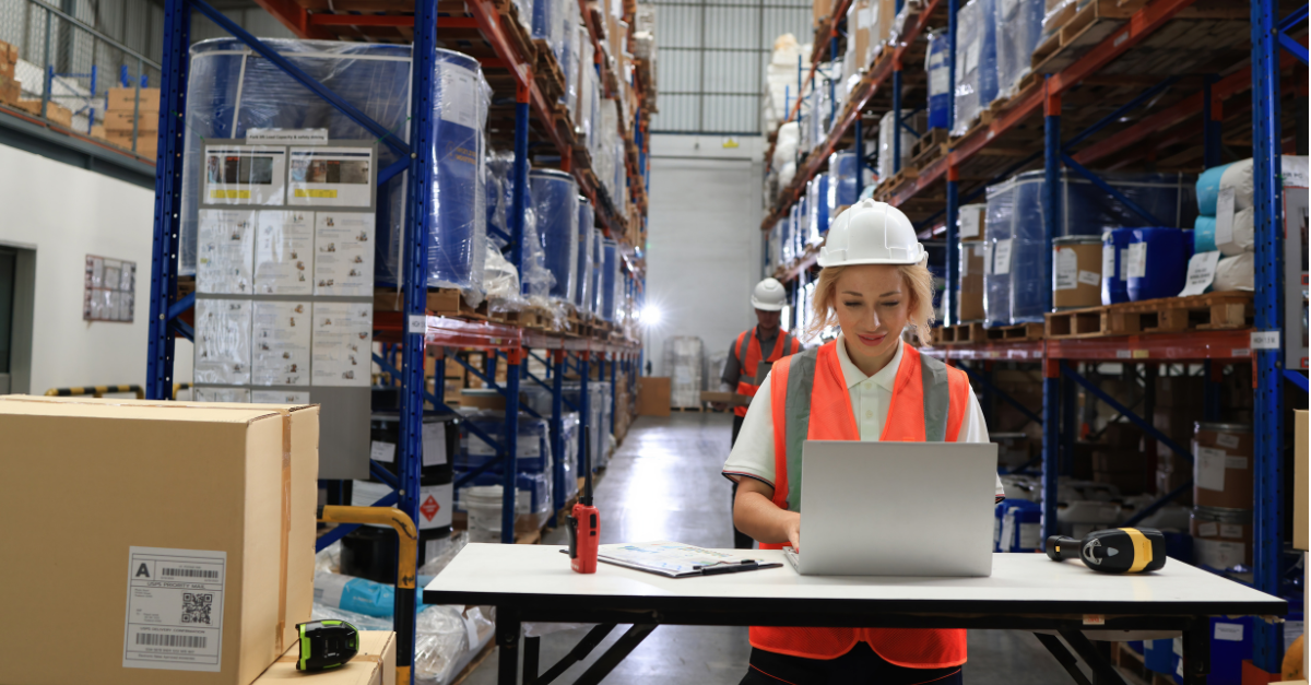 Woman in GMP warehouse using SAP inventory management on a laptop