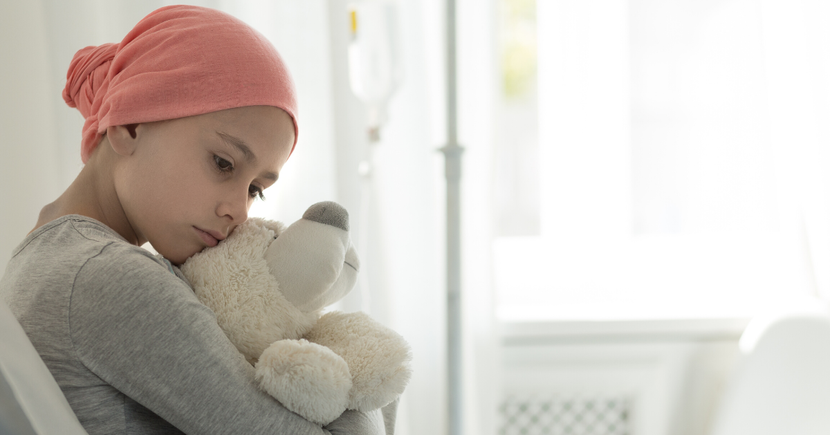 child cancer patient hugging a soft toy bear in hospital